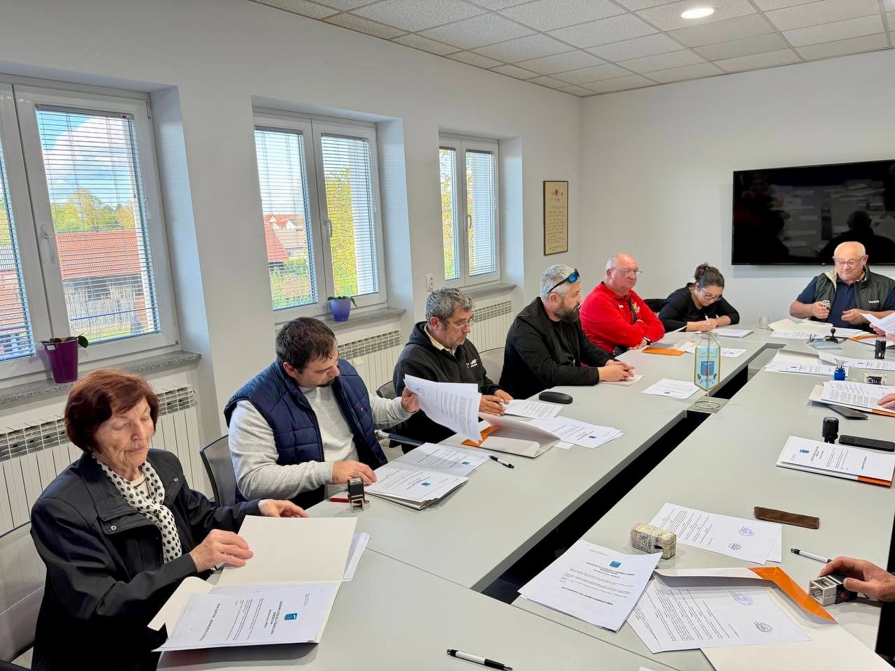 Predstavnici udruga sjede za stolom i potpisuju ugovore o financiranju u prostoriji za sastanke.